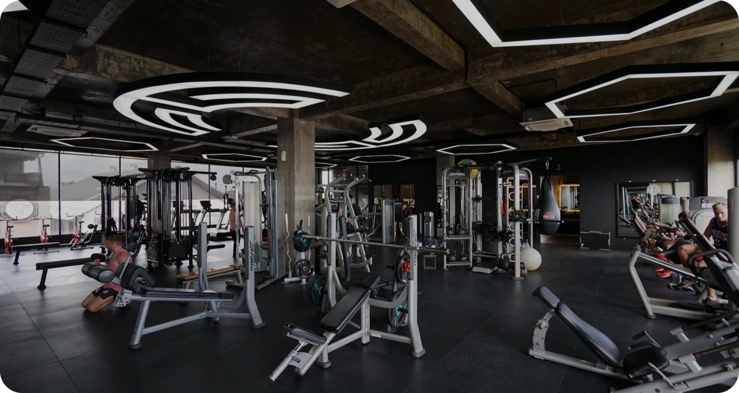 Personal trainer membimbing klien saat latihan angkat beban di gym