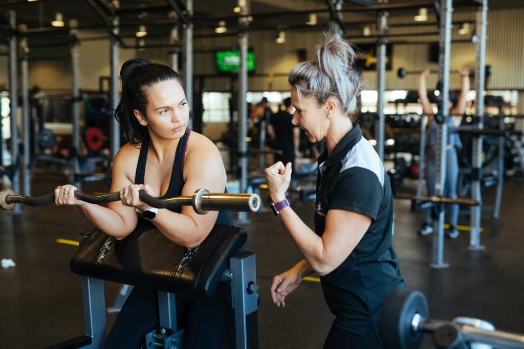 Trainer motivating a client during a weight training Bali coaching session as part of personalized workout plans at Surya Gym Bali.