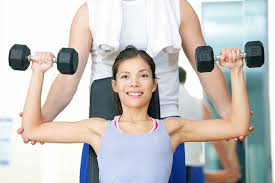 Happy woman lifting dumbbells showing the benefits of weight training Bali for strength and confidence.