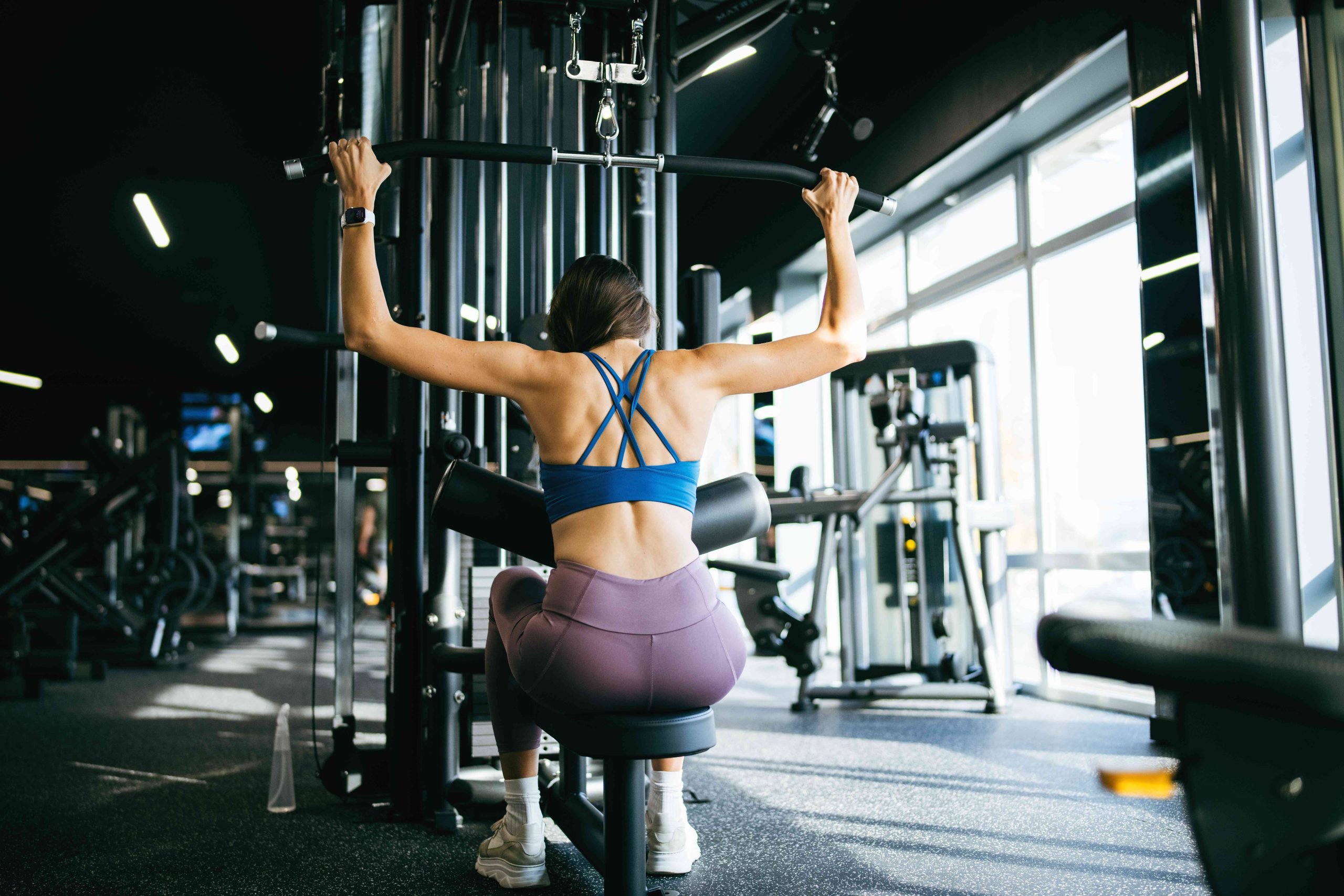 Woman doing lat pulldown exercise as part of her weight training Bali routine.